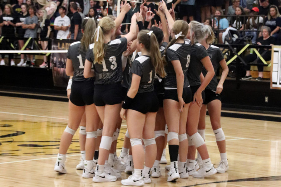 The varsity volleyball team huddles together during the Sept. 24 match. 