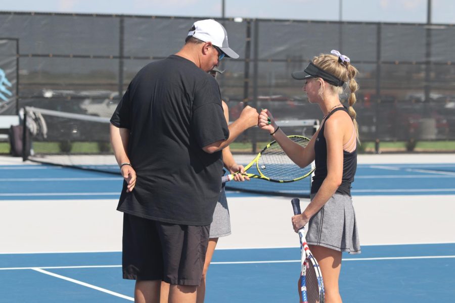 Coach Darby Norman fist bumps sophomore Gabby Dishong.
